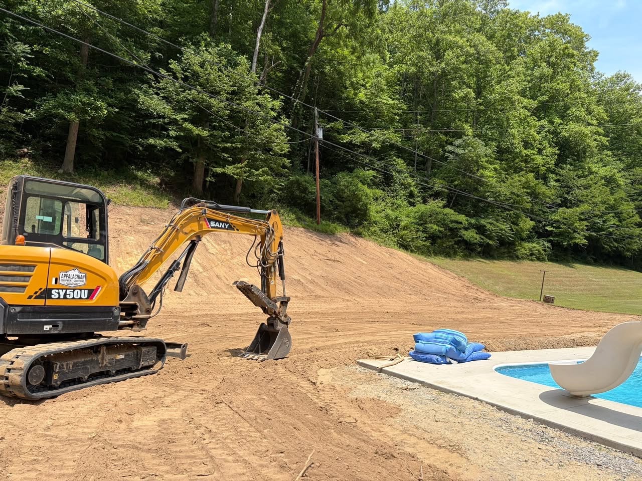 Excavator grading a pool site for Premier Builders