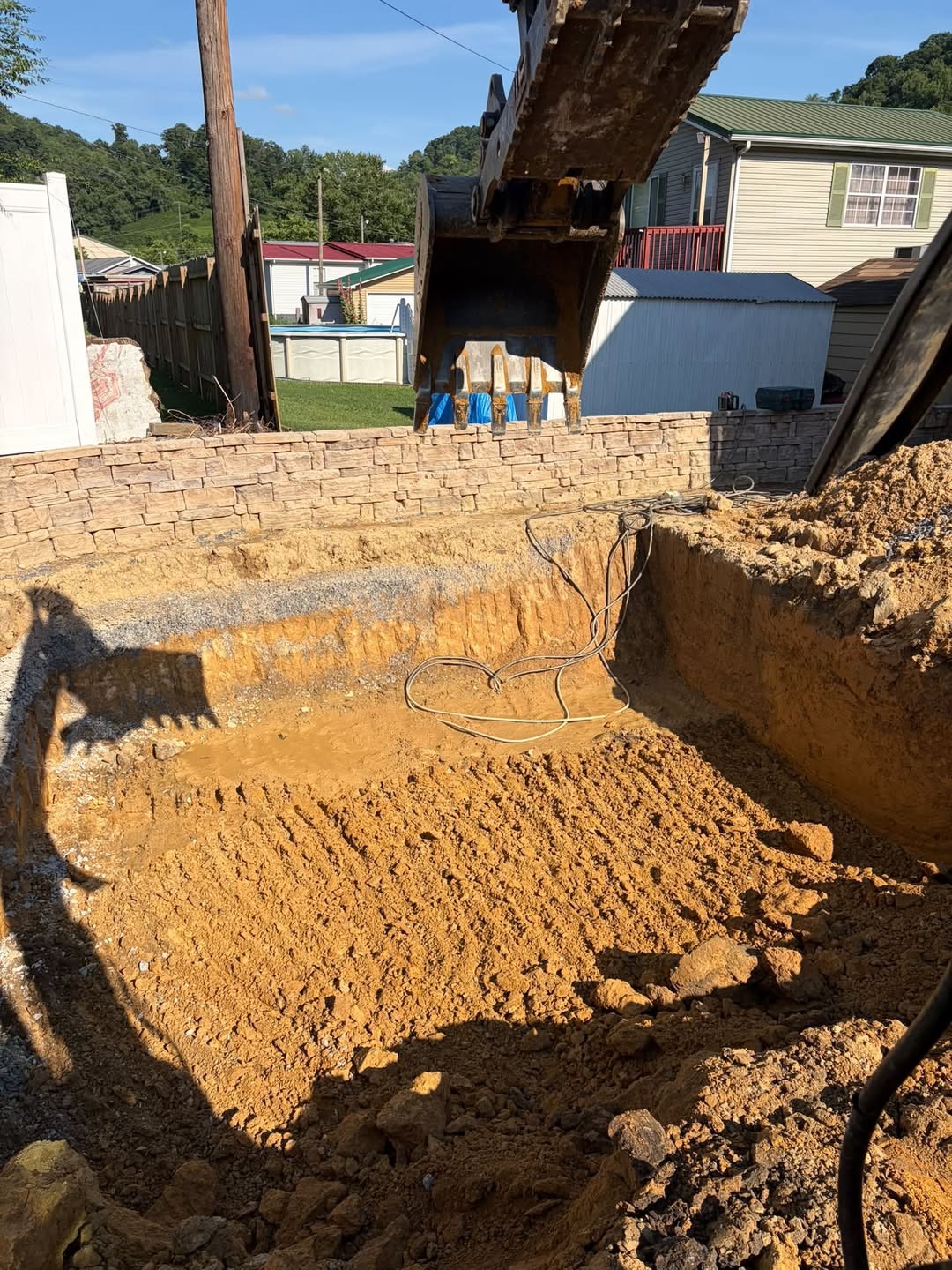 Pool excavation behind a stone retaining wall
